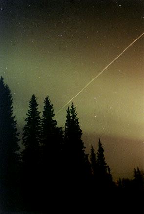 Shooting star seen in the Alaskan evening sky during the Leonid meteor shower. What appear to be clouds in the background is actually the Aurora. 